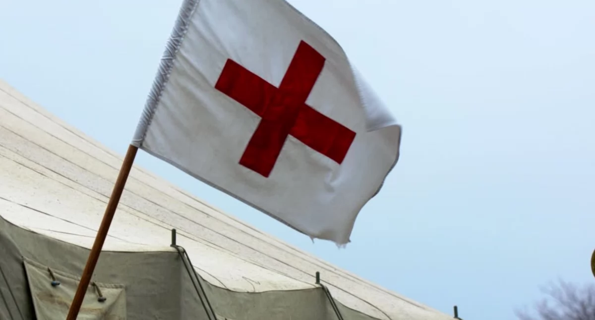 Biała flaga z czerwonym krzyżem - symbol szpitala polowego