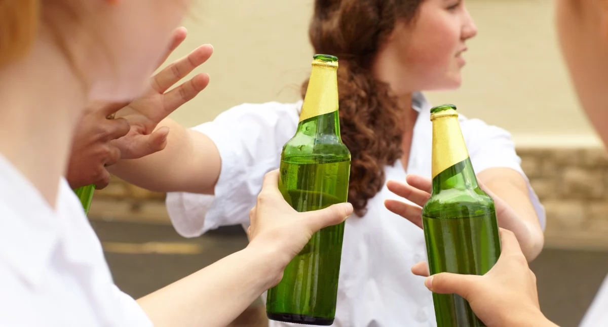 Na zdjęciu: dziewczyna odpychająca butelki z alkoholem 
